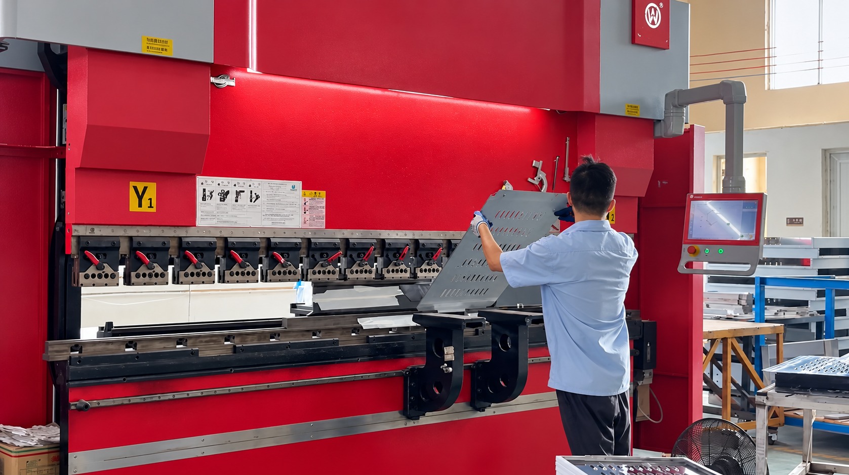 Factory worker operating a sheet metal bending machine